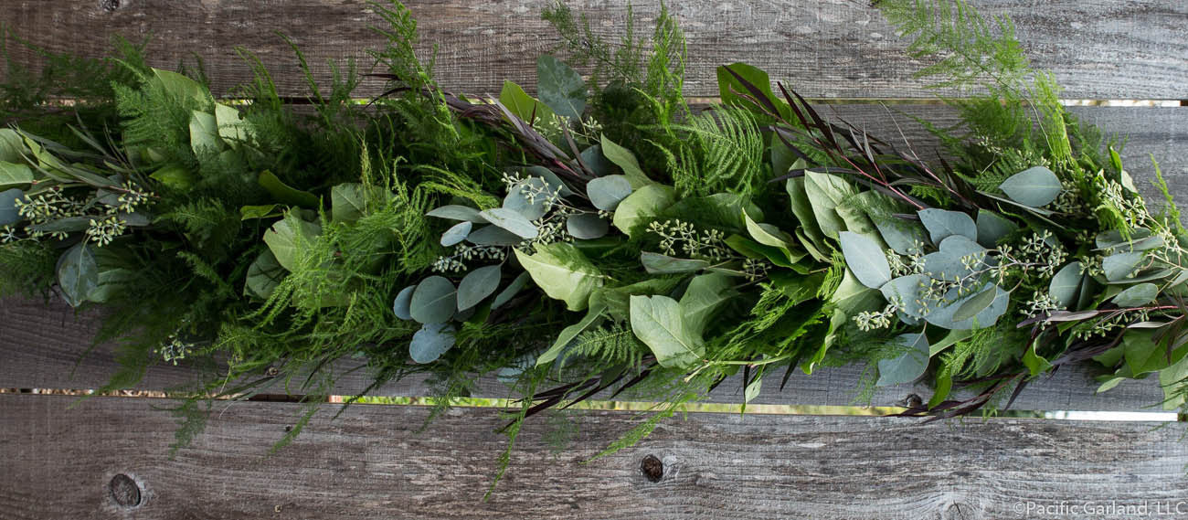Beautiful Fresh Designers Choice Extra Full Four Item Garland with Plumosa, Agonis, Salal and Seeded Eucalyptus on Wood Fence